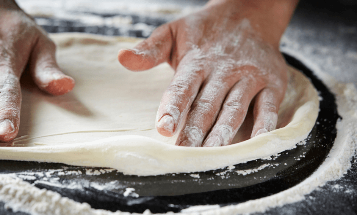 Man pressing out pizza dough